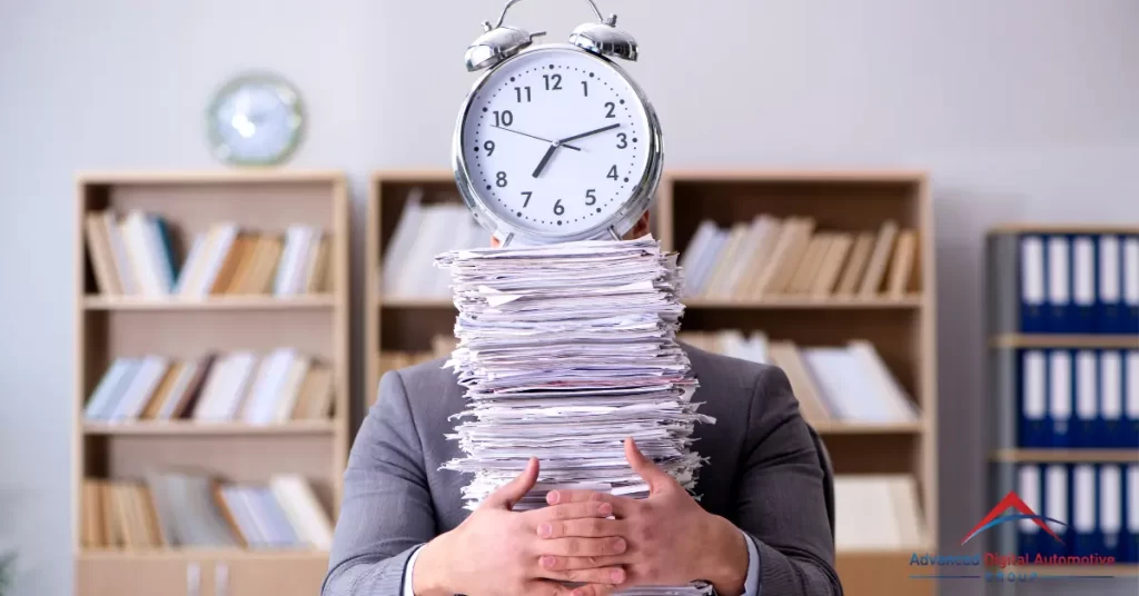 Man embracing a pile of paperwork with an alarm clock on top.