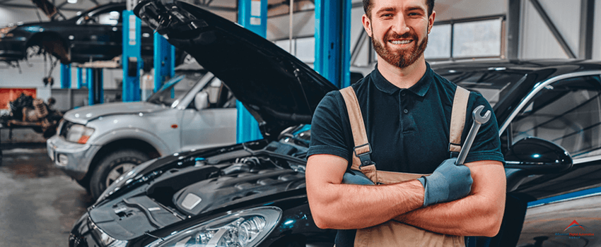 Close up view of a smiling mechanic inside his auto repair shop